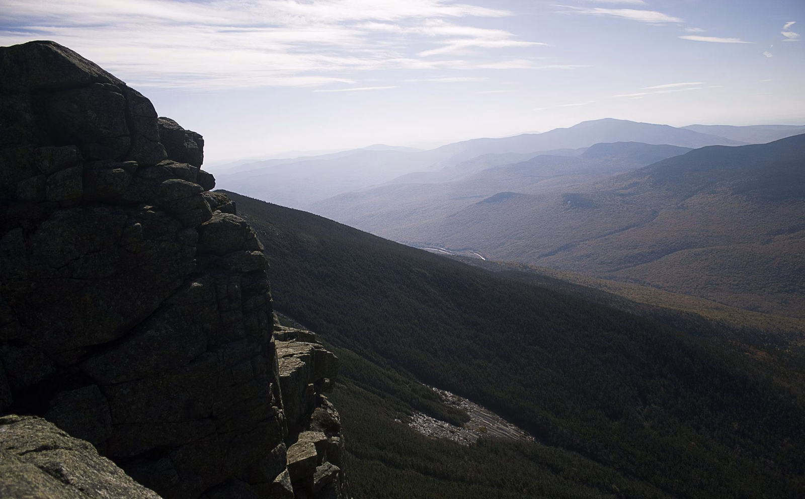 Granite outcrop on a high ridge above a hazy forested mountain valley in Franconia Notch State Park
